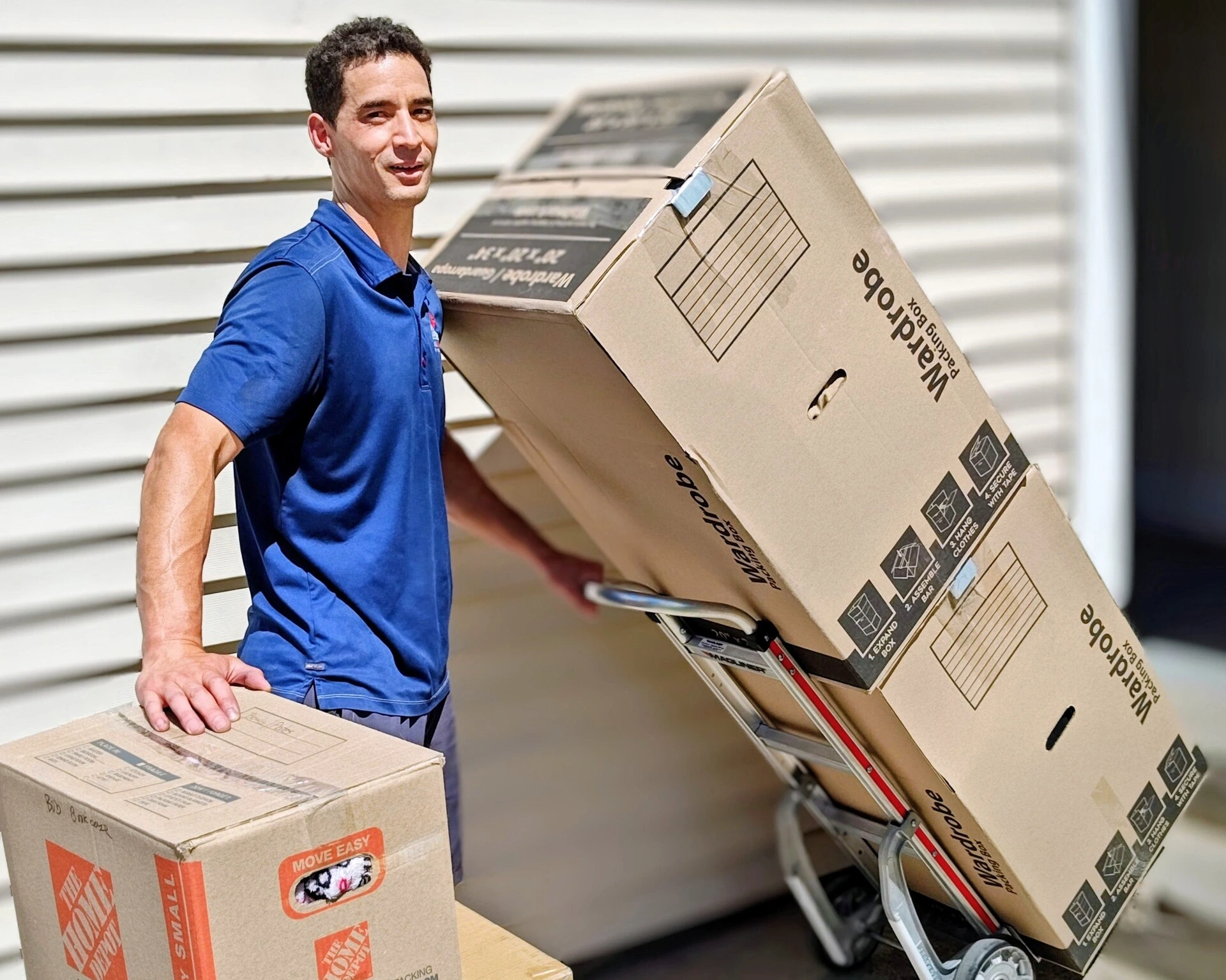 Mover wheeling stacked wardrobe boxes on a dolly during an apartment move
