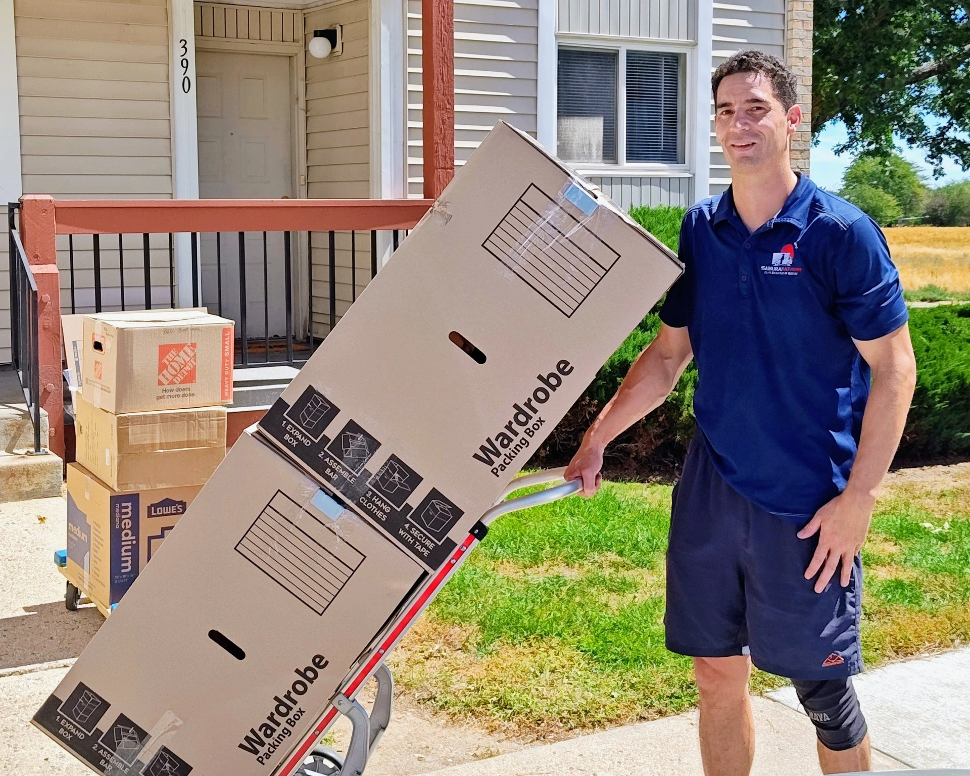 Mover with a dolly delivering boxes outside a house.