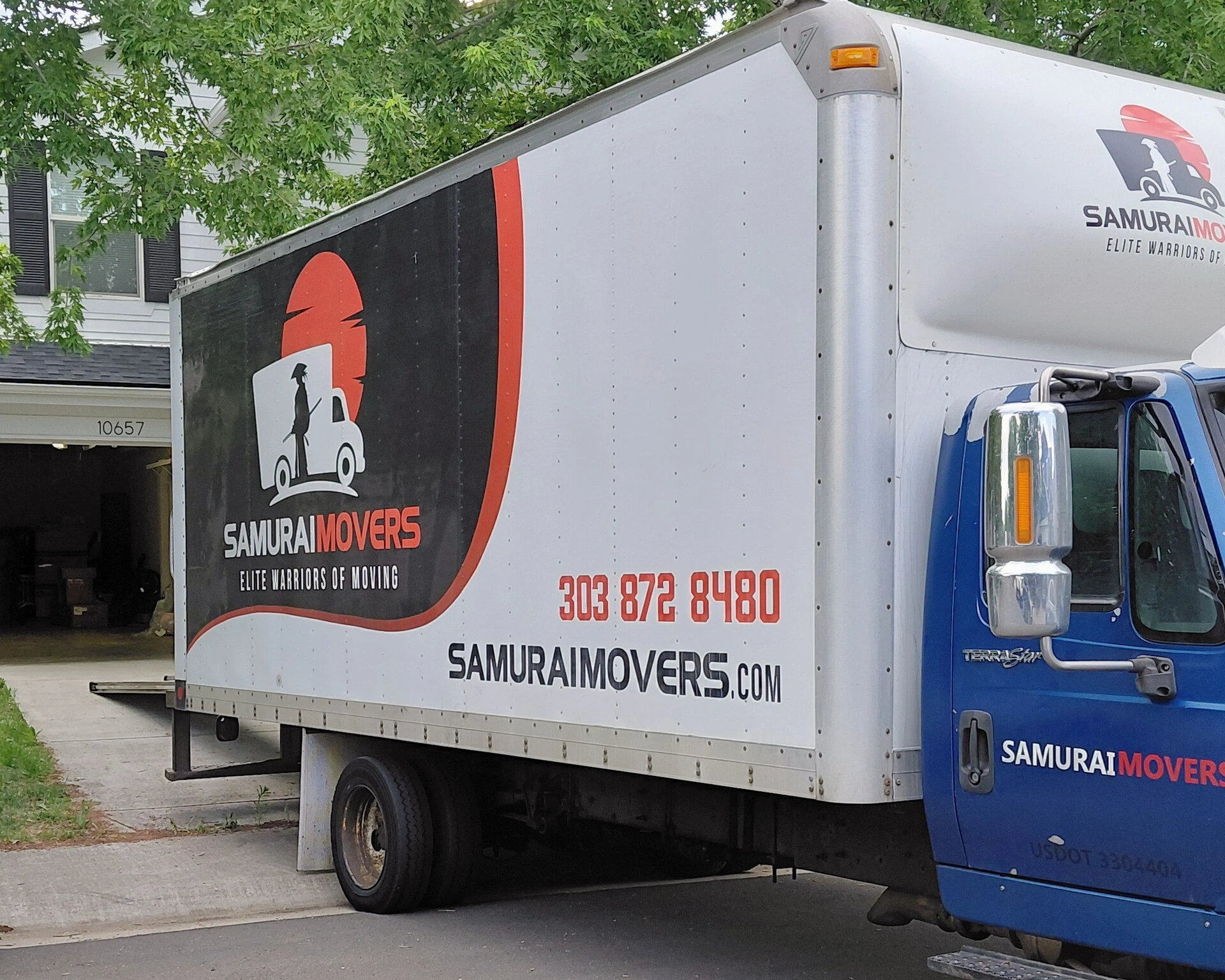Samurai Movers truck with logo and contact info in a residential area.
