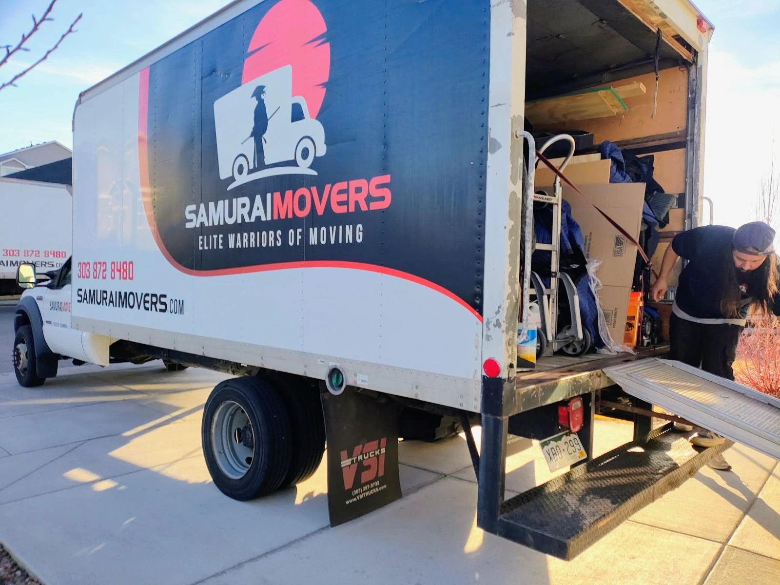 Mover loading a hand truck into a Samurai Movers truck with the liftgate lowered