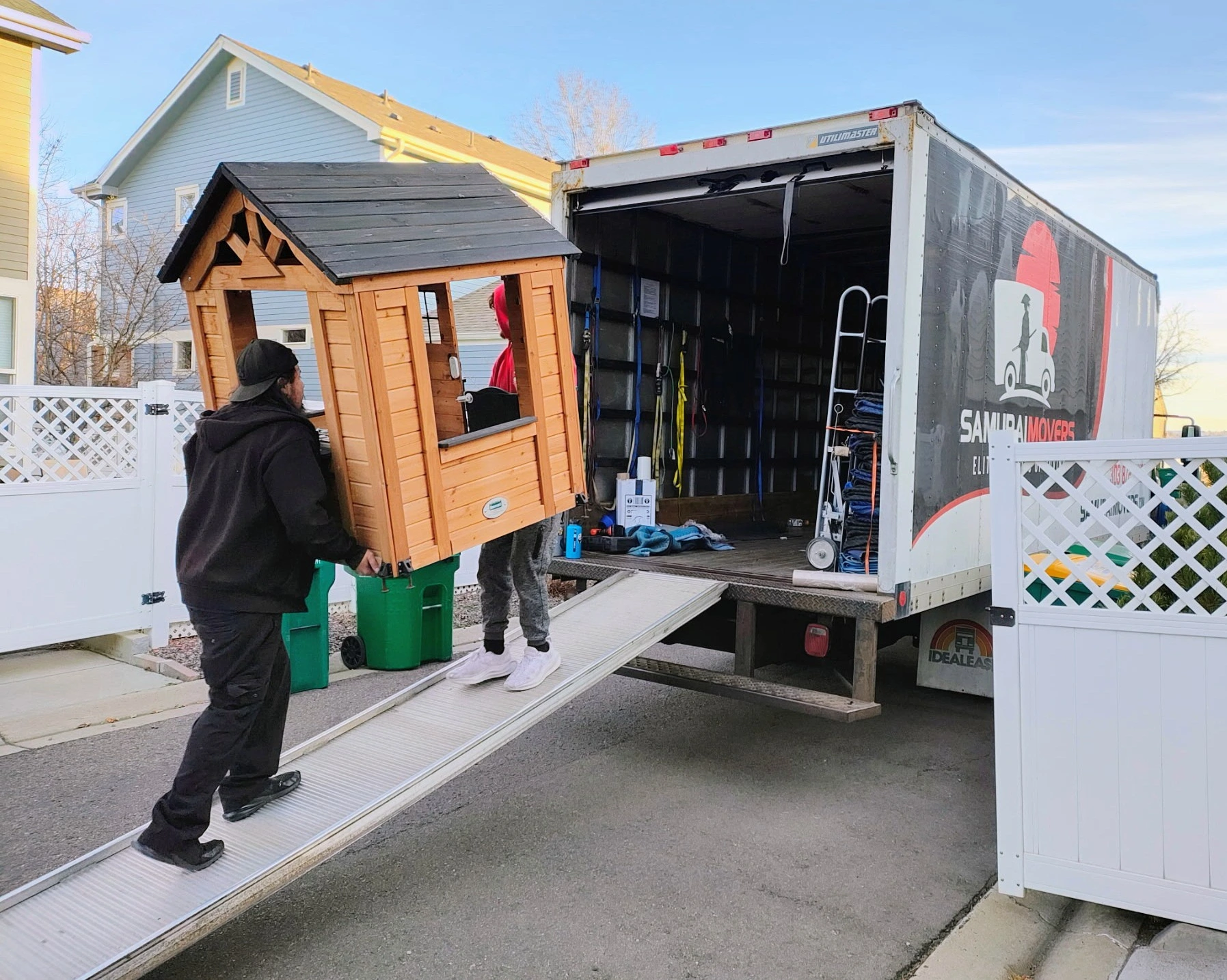 Broomfield CO movers walking a backyard playhouse toward an open moving truck